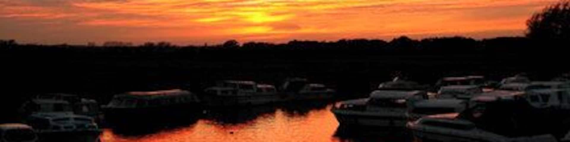Sunset at Potter Heigham, Norfolk. The influence of the October sky enhances the natural beauty of Broadland. Here, the hire boats are moored for the night.