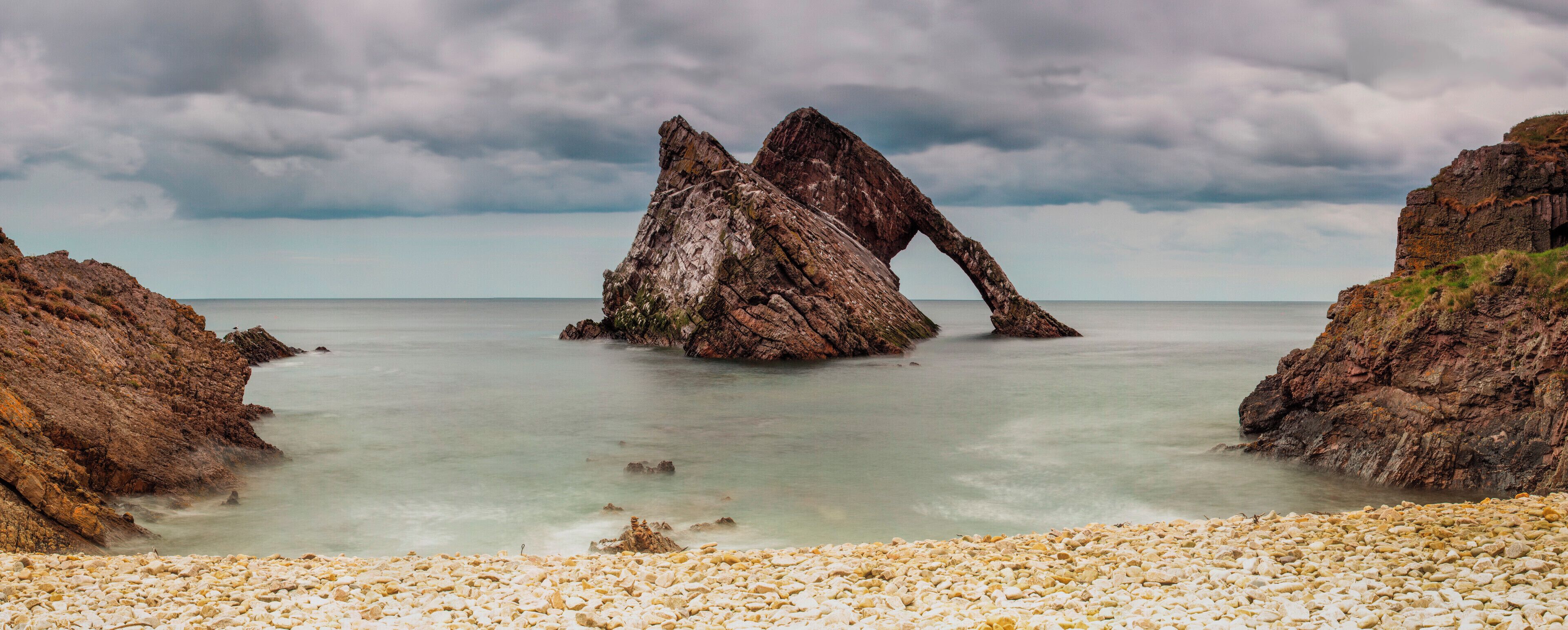 A rocky coastal landscape with a prominent rock formation in the center.