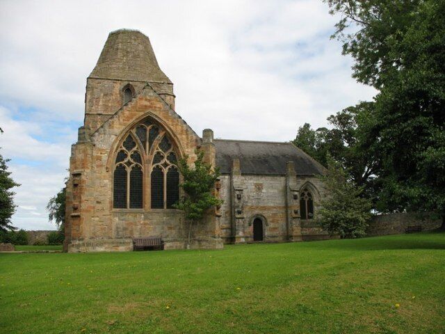 A historic stone church with a pointed tower and large arched windows.