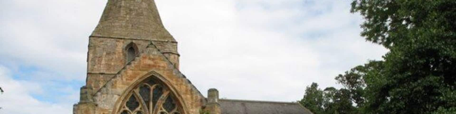 A historic stone church with a pointed tower and large arched windows.