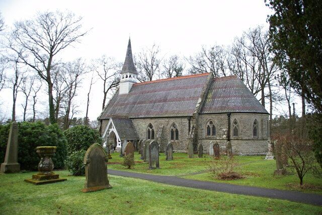 A church with a pointed steeple, surrounded by a cemetery with headstones and a stone urn.