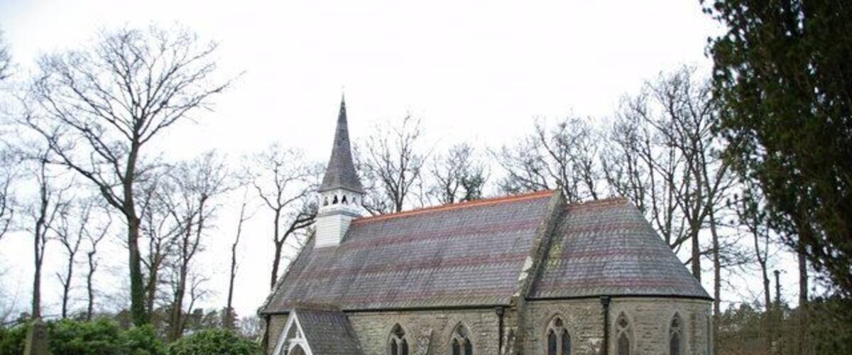 A church with a pointed steeple, surrounded by a cemetery with headstones and a stone urn.