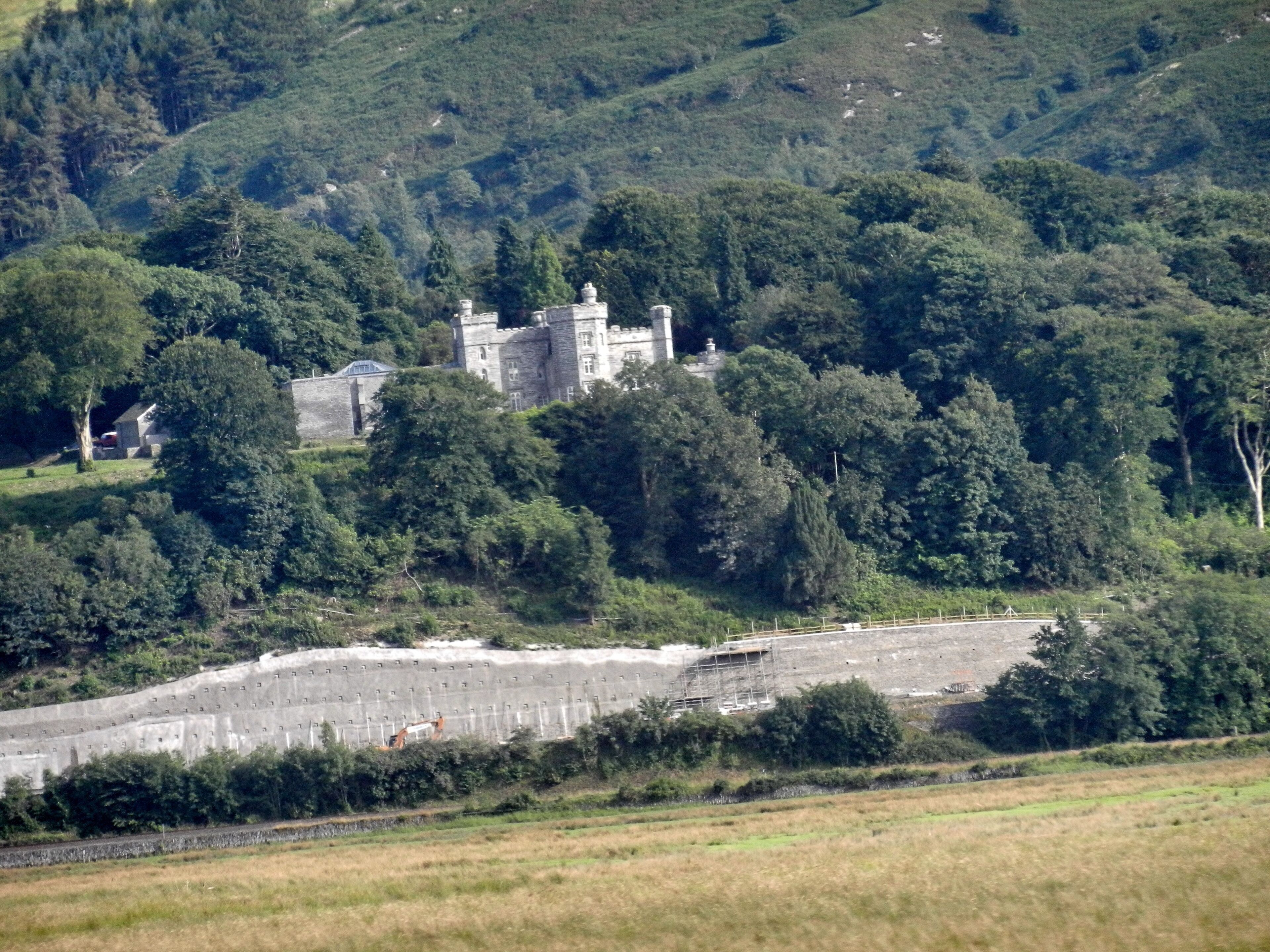 A castle surrounded by dense forest and fields.