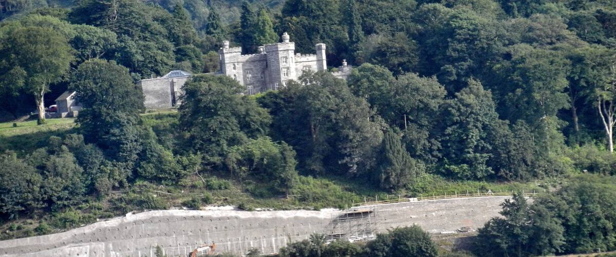 A castle surrounded by dense forest and fields.