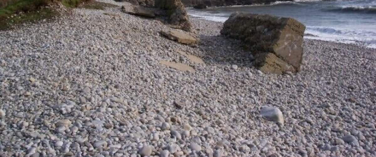 Gilman Point from storm beach at Morfa Bychan Gilman Point is formed from beds of Carboniferous Limestone seen here dipping seawards.
