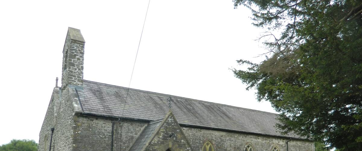 A stone church with a tall bell tower and a graveyard in front.