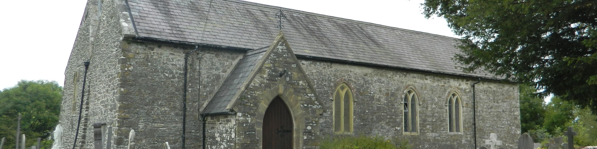 A stone church with a tall bell tower and a graveyard in front.