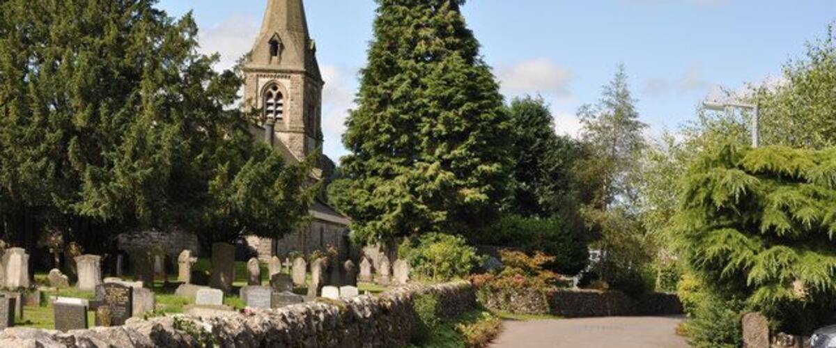 Church Walk, Parwich, Derbyshire, with the tower and spire of St Peter's parish church on the left