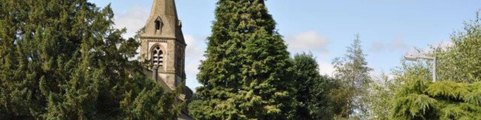 Church Walk, Parwich, Derbyshire, with the tower and spire of St Peter's parish church on the left