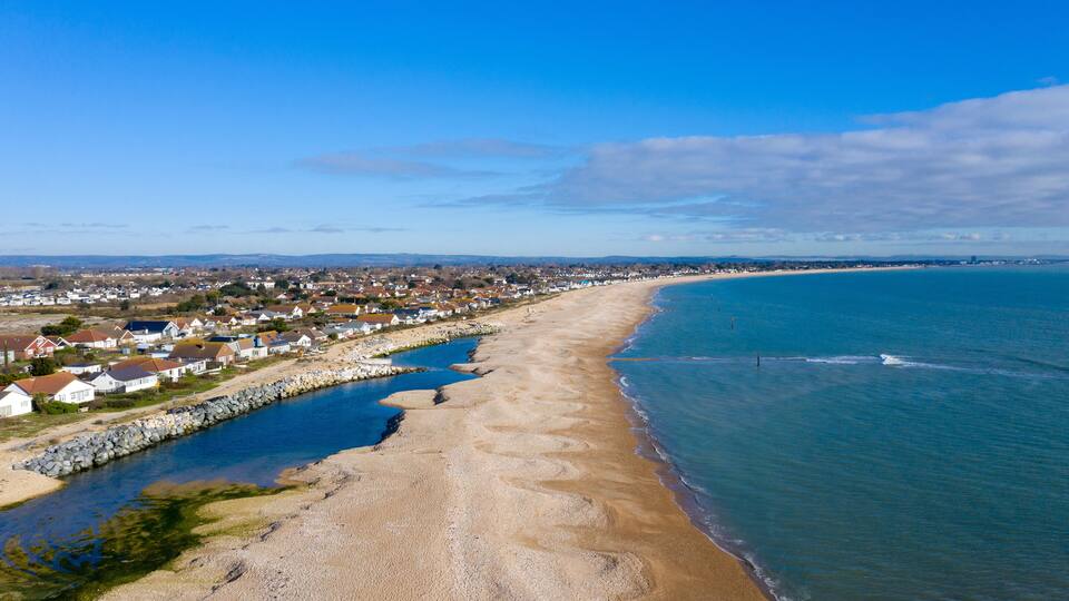 A coastal town with a sandy beach, a rocky shoreline, and a clear blue sky.