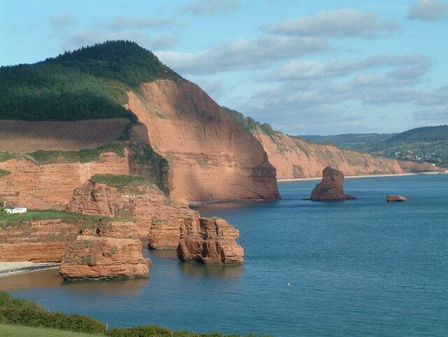 A coastal landscape with cliffs, a beach, and a clear sky.