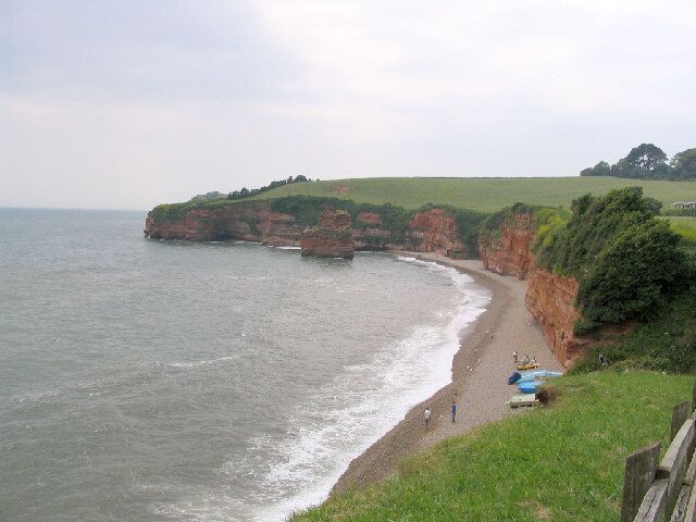 A coastal landscape with cliffs, a beach, and a grassy hill.