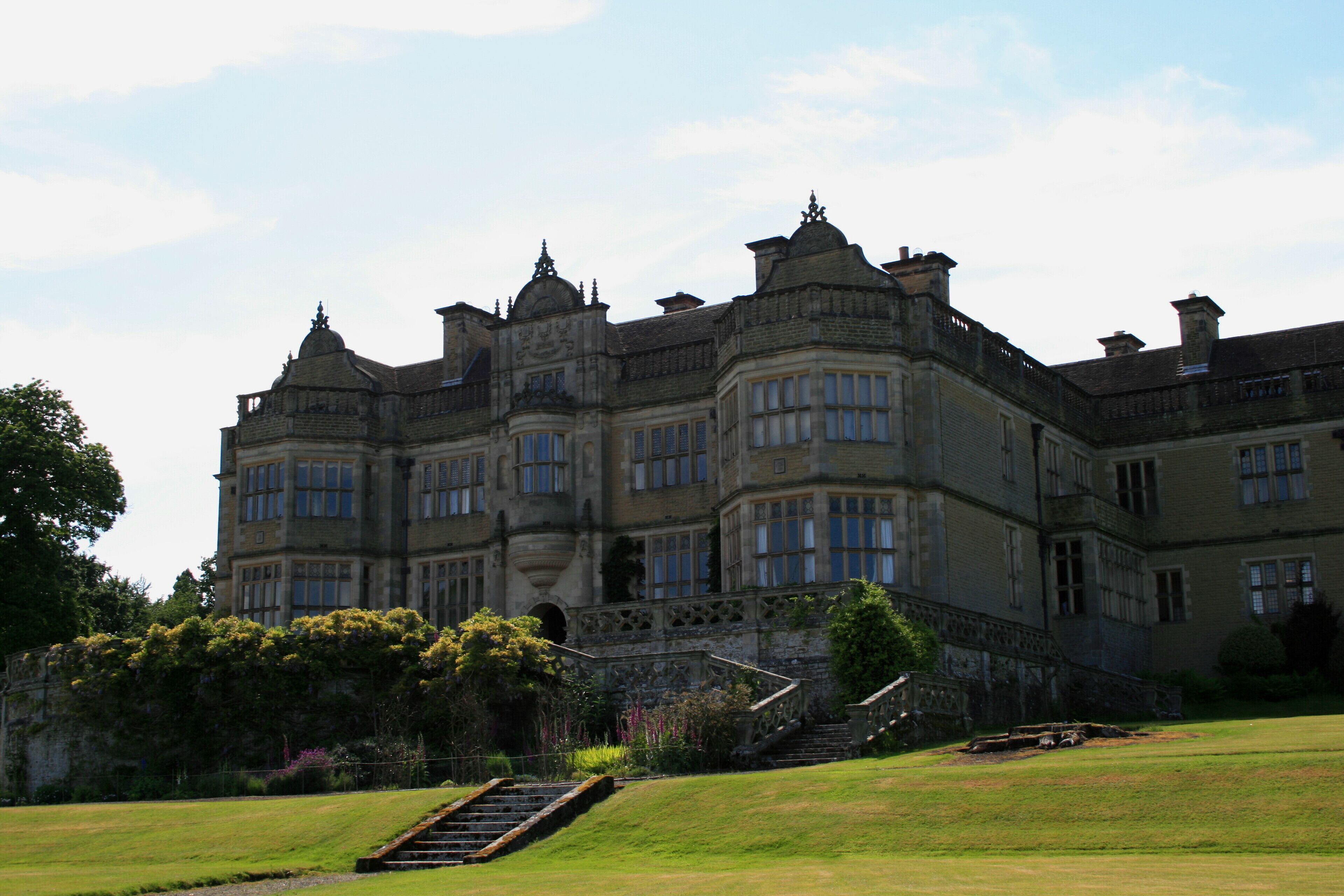 A large, historic building with multiple towers and a well-maintained garden.