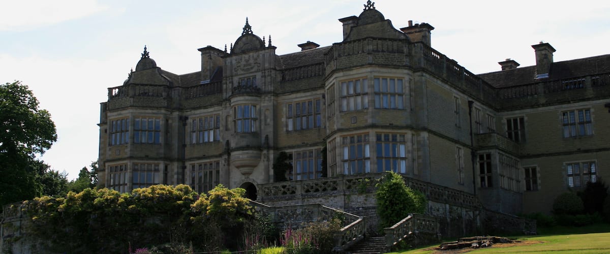 A large, historic building with multiple towers and a well-maintained garden.