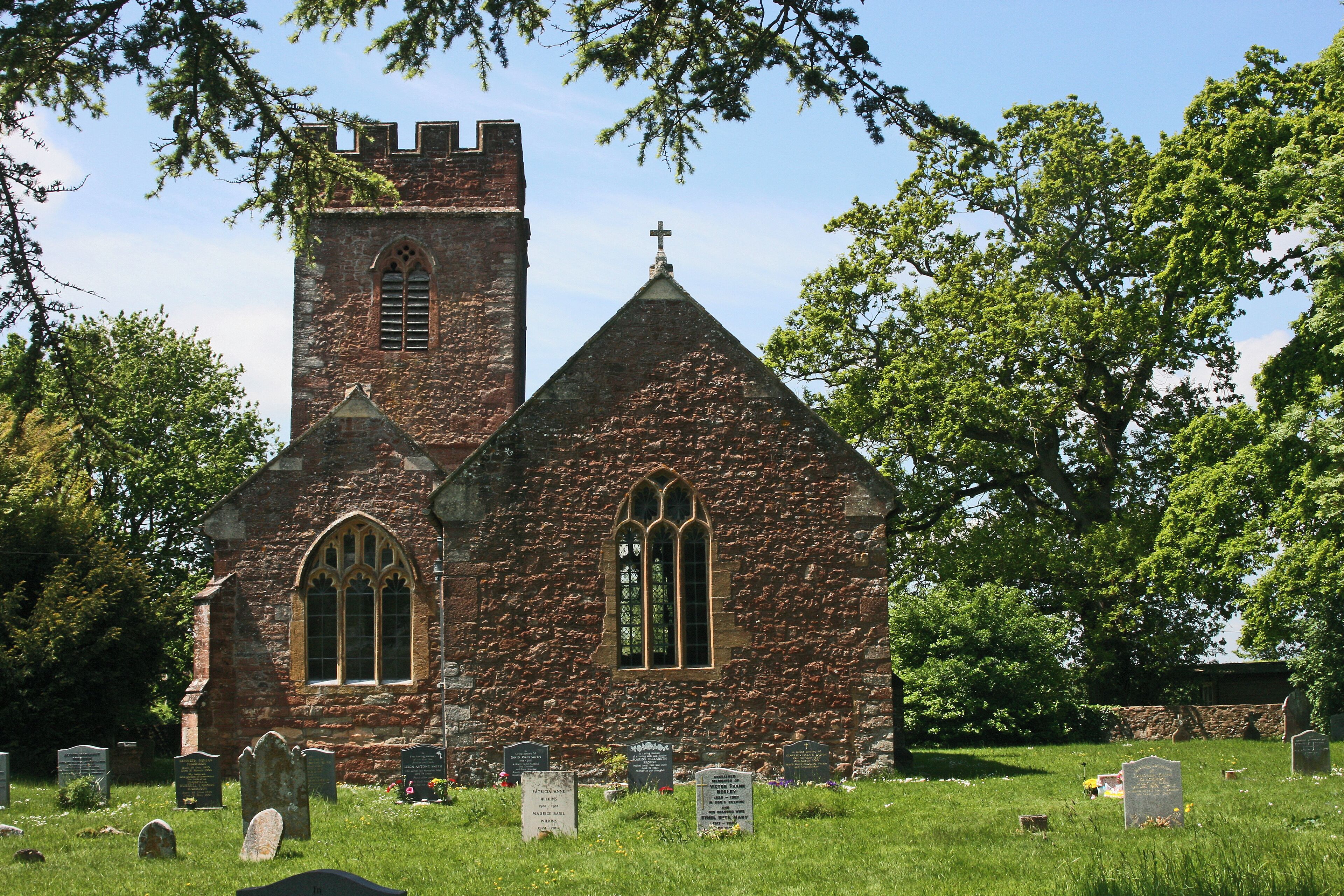 A historic church with a tower and arched windows, surrounded by a cemetery with headstones.