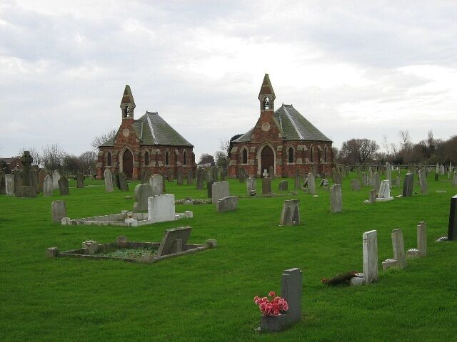 A cemetery with two prominent church buildings and numerous gravestones.