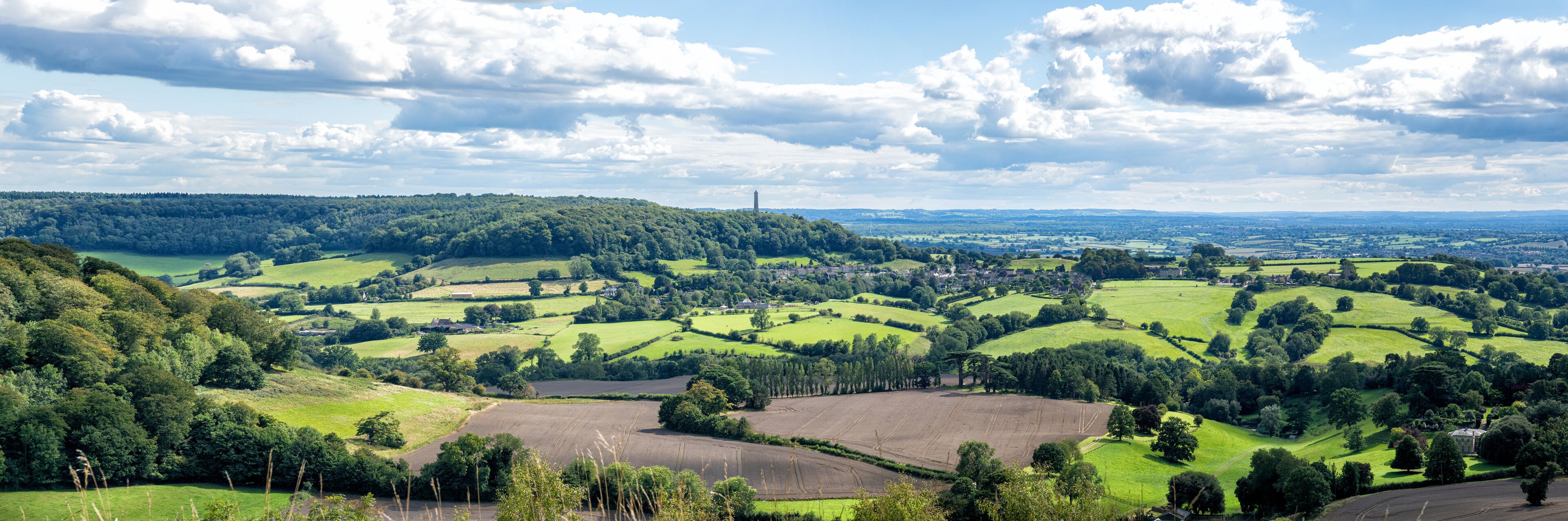 Rolling green hills, a distant windmill, and a village in the valley.