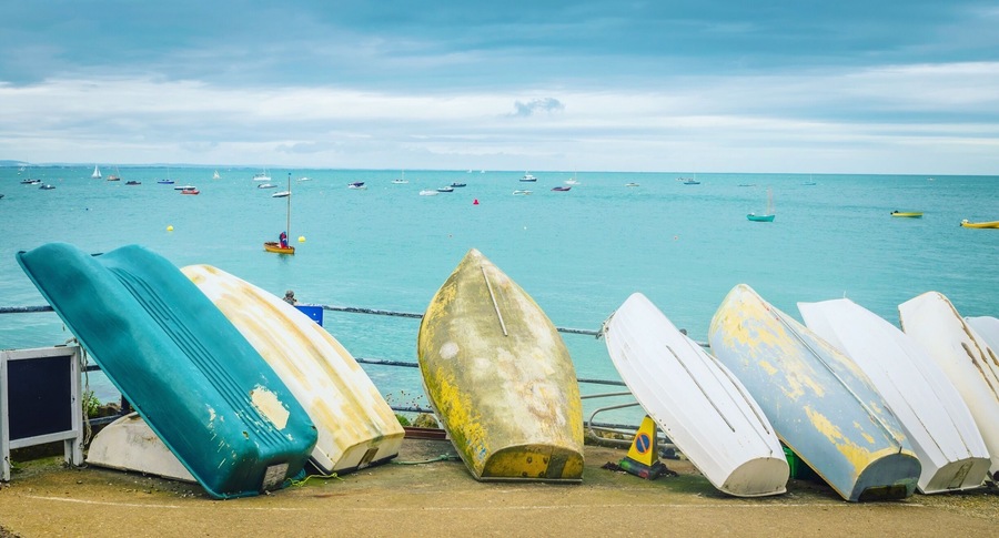 Boats resting at shore.The Isle of Wight is an island off the south coast of England. It’s known for its beaches and seafront promenades such as sandy Shanklin Beach and south-facing Ventnor Beach, which is dotted with vintage beach huts
