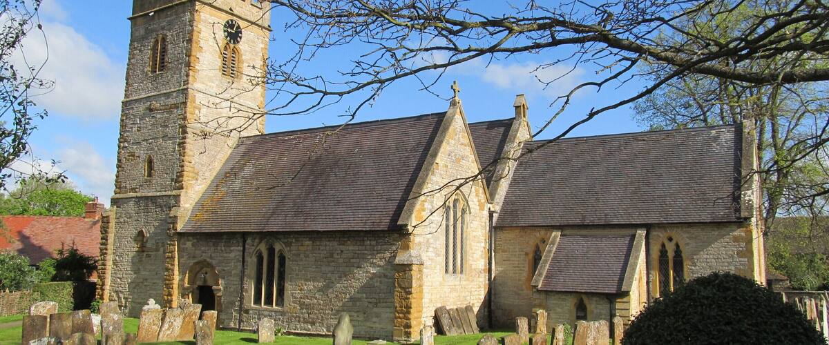 A historic church with a tall tower and a graveyard in front.