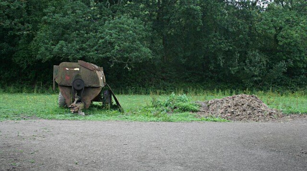 An old 'muck spreader' This farm machinery was seen in a small field between the road and woodland. On the right is a pile of dirty straw, just the sort of thing which this machine might have thrown onto the fields.