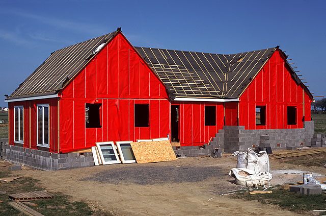 A red barn under construction with a metal roof and wooden siding.
