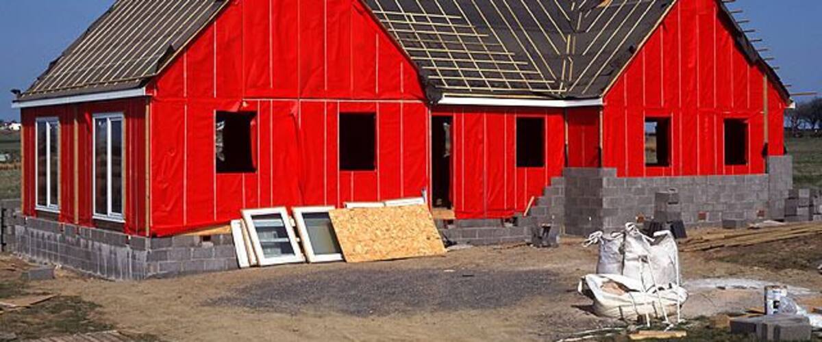 A red barn under construction with a metal roof and wooden siding.