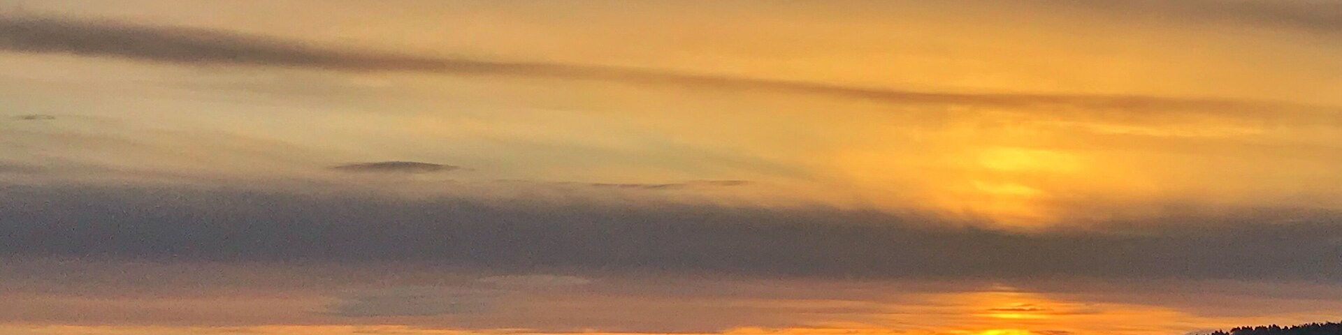 Un atardecer sobre un paisaje montañoso con un primer plano brumoso.