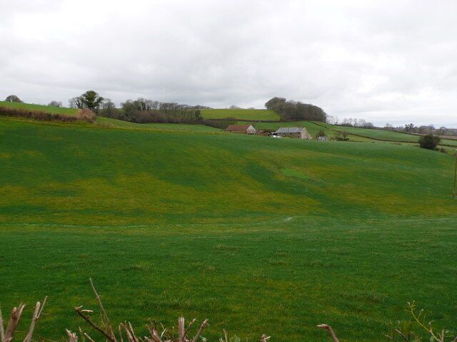 A green field with a small house in the distance.