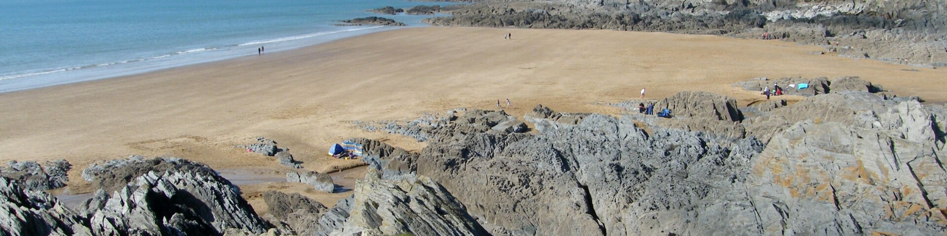 Un litoral rocoso con una playa de arena y zonas cubiertas de hierba.