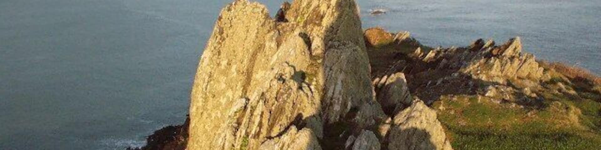 Un paisaje costero rocoso con una destacada formación de piedra caliza.