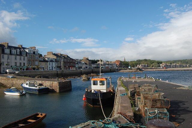 A harbor with boats, a stone wall, and buildings along the water.