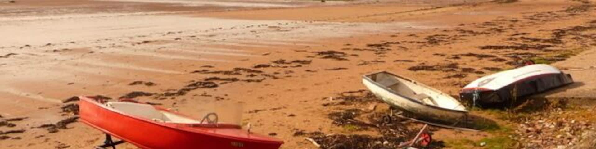 Millport: looking west across Kames Bay The gently sloping sands of Kames Bay, with the frontages of Kelburn Street to the right and the Isle of Arran outline a dramatic backdrop.