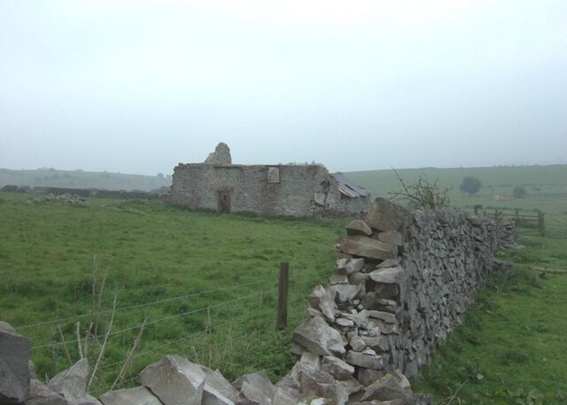 Derelict farm buildings above Cressbrook Dale This building looming out of the drizzle will soon collapse completely. The wall demonstrates the hard limestone of the area well.