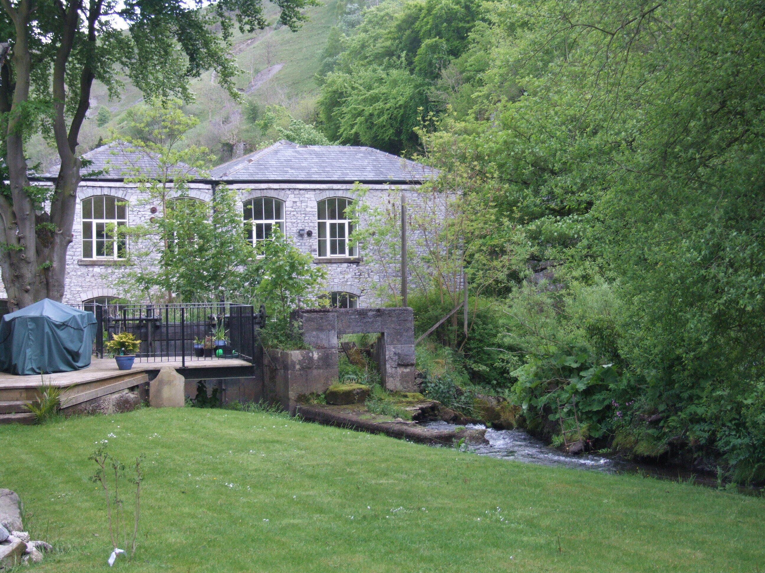 A stone house with a garden and a stream.