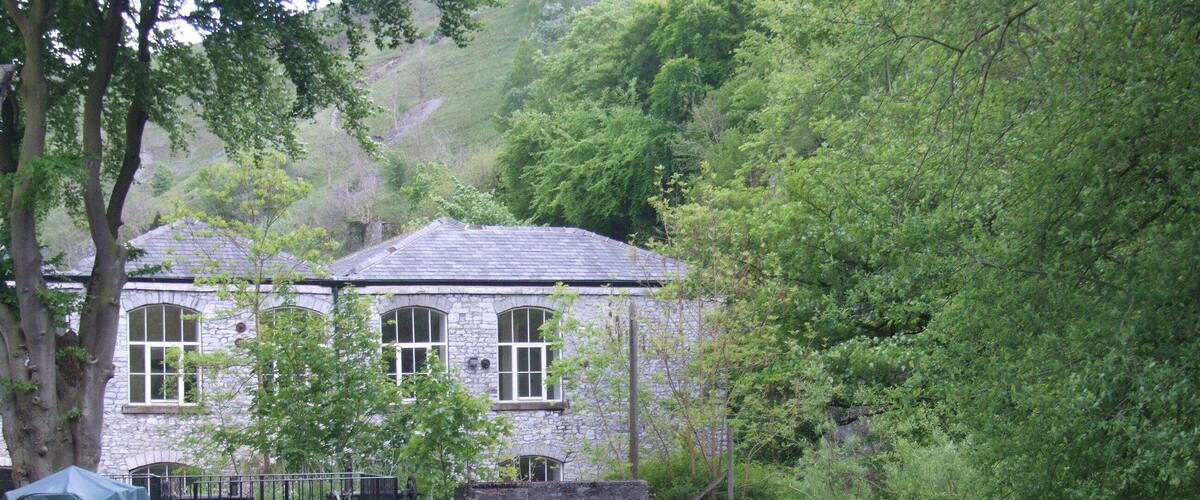 A stone house with a garden and a stream.