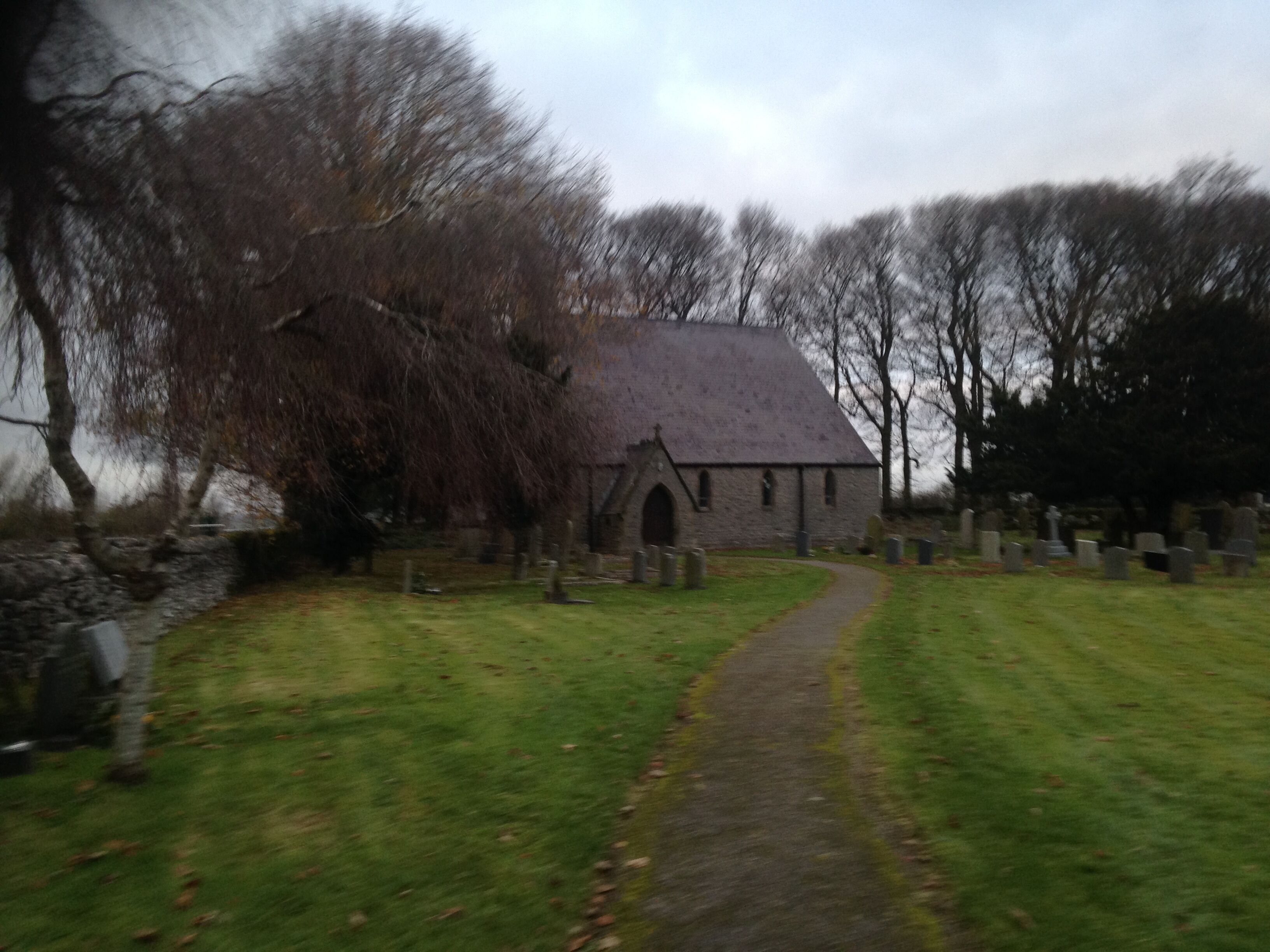 A church with a stone roof and a graveyard with headstones.