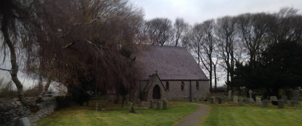 A church with a stone roof and a graveyard with headstones.