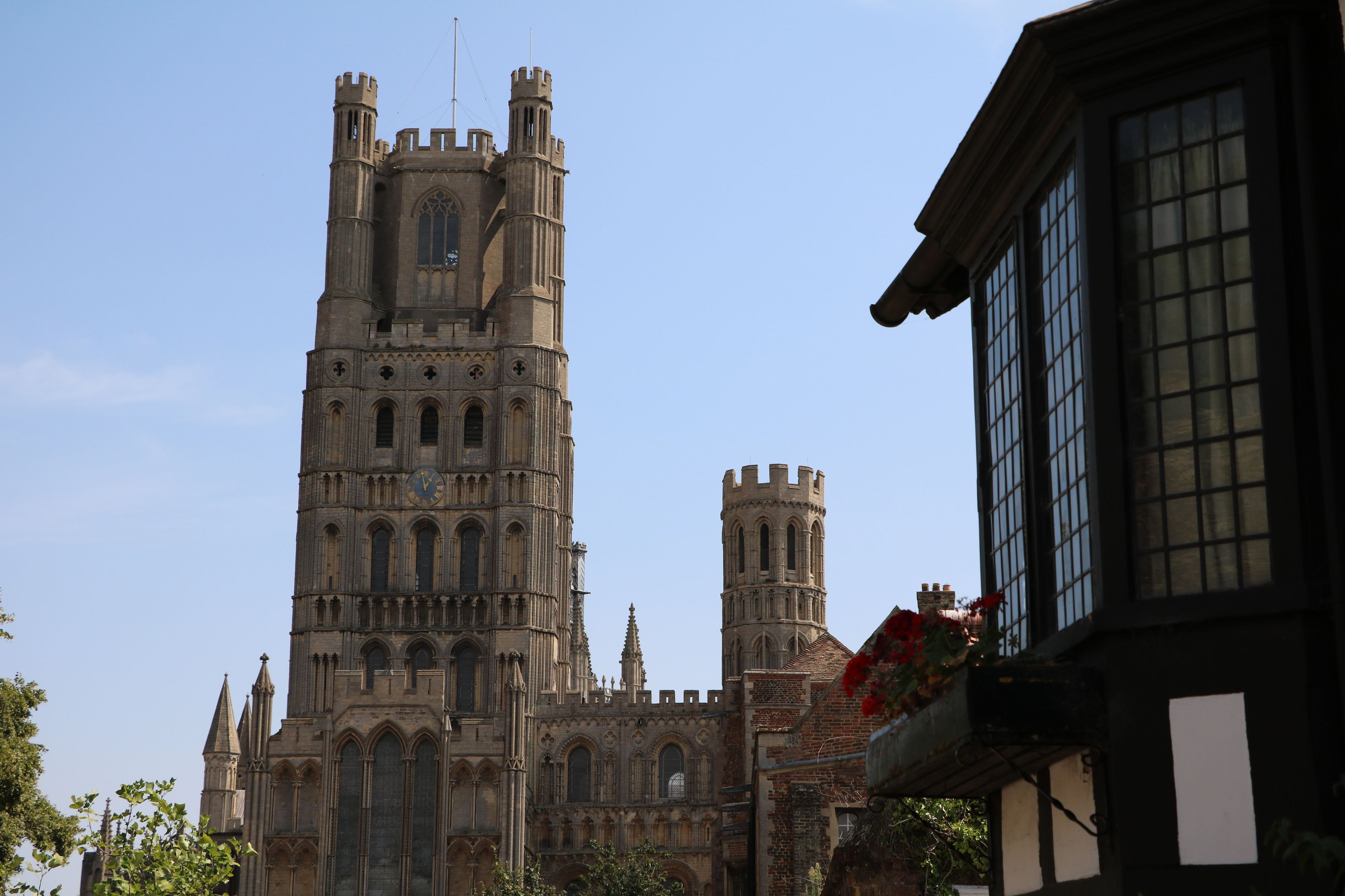 A historic cathedral with a tall clock tower, intricate Gothic architecture, and a clear blue sky.