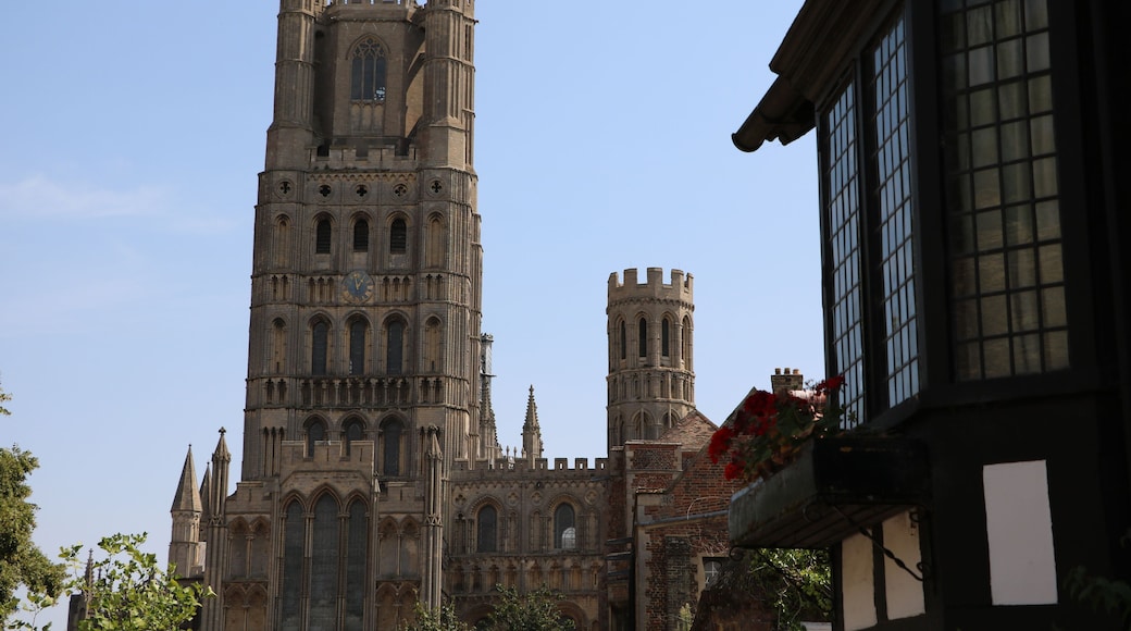 A historic cathedral with a tall clock tower, intricate Gothic architecture, and a clear blue sky.