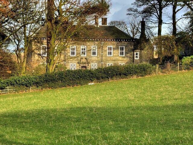 A stone house with a green lawn in front.