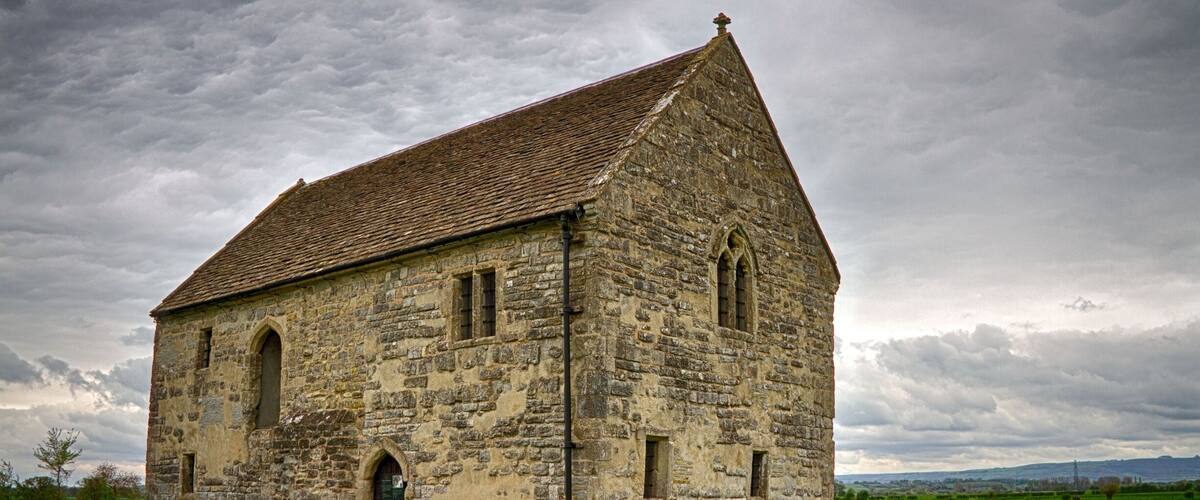 A stone church with a steep roof and arched windows.