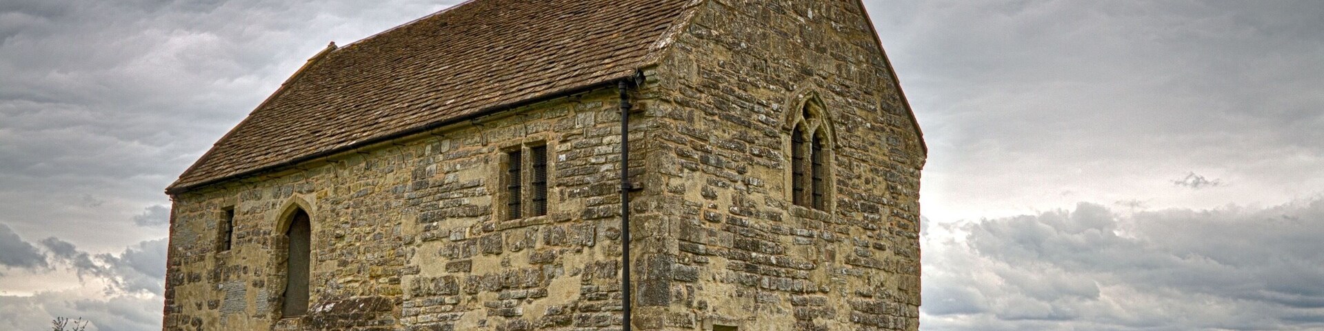 A stone church with a steep roof and arched windows.
