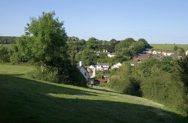 Green space, Marldon Two paths, diverging from the point at which the photo was taken, cross this pleasant green area near the old heart of Marldon. The couple with the dog are descending Marldon Footpath 4, while Footpath 3 curves to the left along the terrace. The large house in the trees ahead is Marldon House.