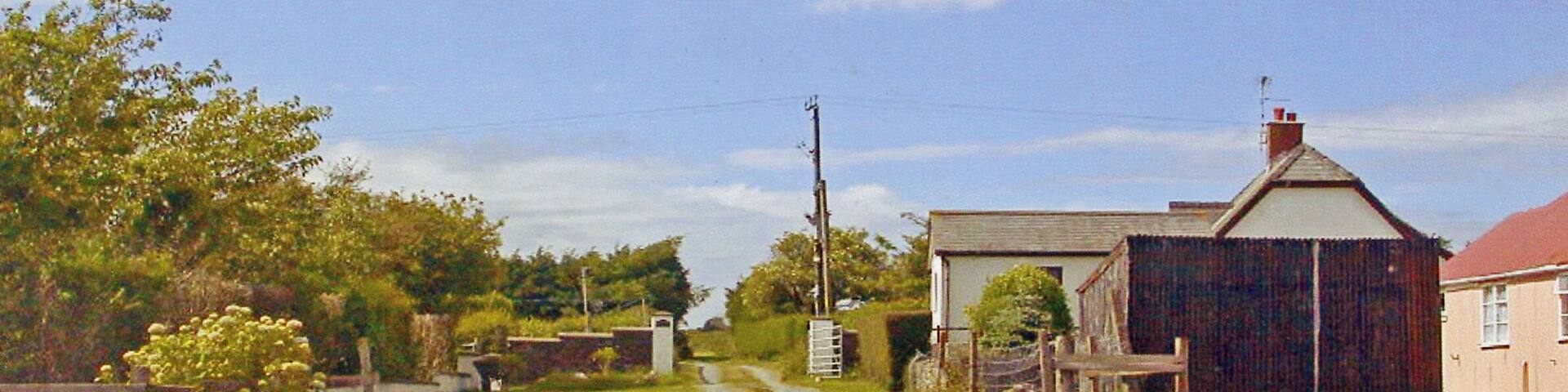 A rural road leading to a farmstead with a barn and a house.