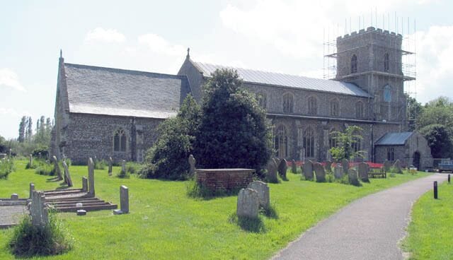 A church with a stone facade, a tower, and a graveyard with headstones.
