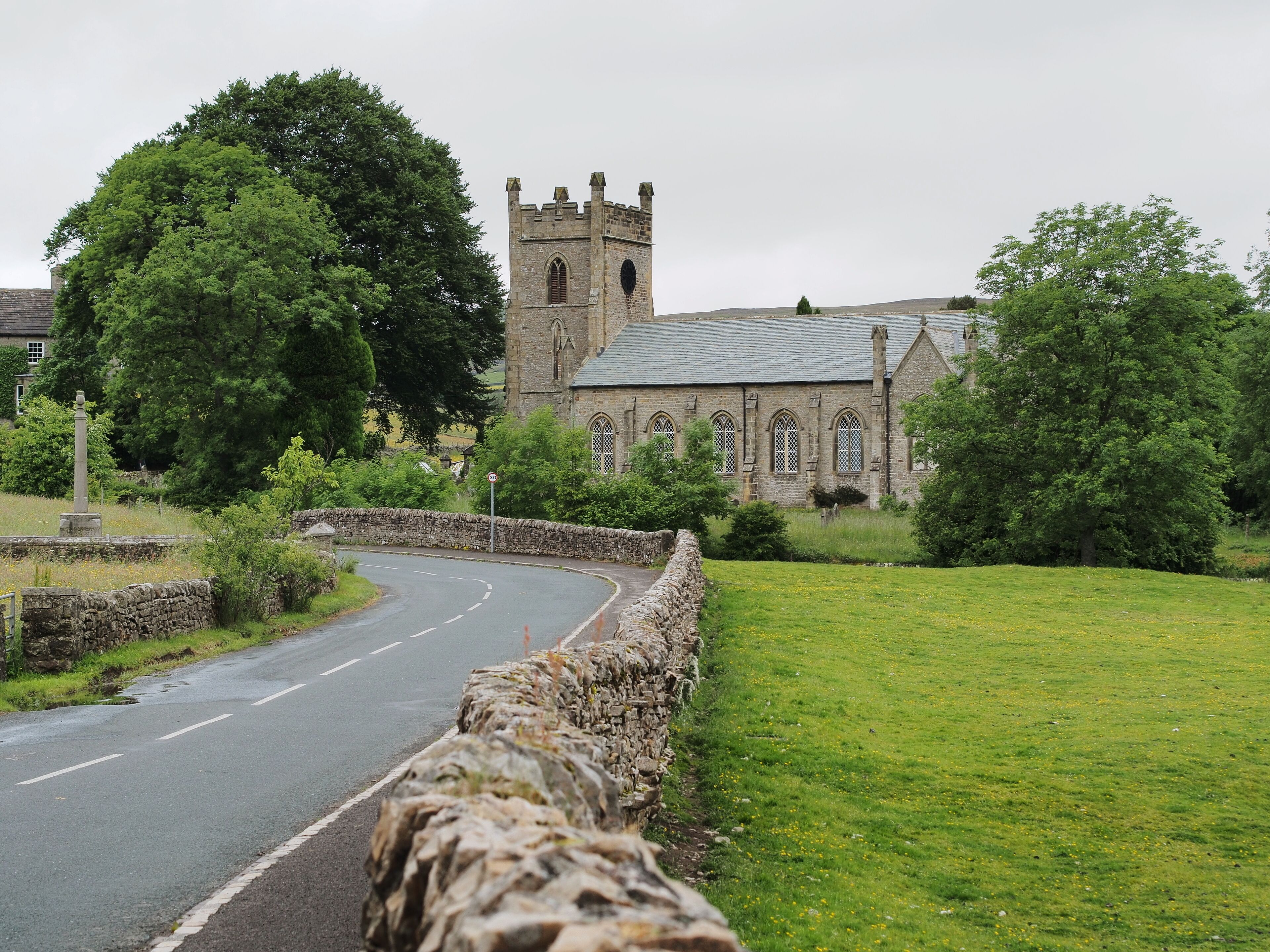 A stone wall, a road, and a church with a tower.