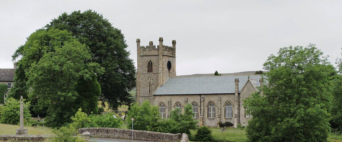 A stone wall, a road, and a church with a tower.