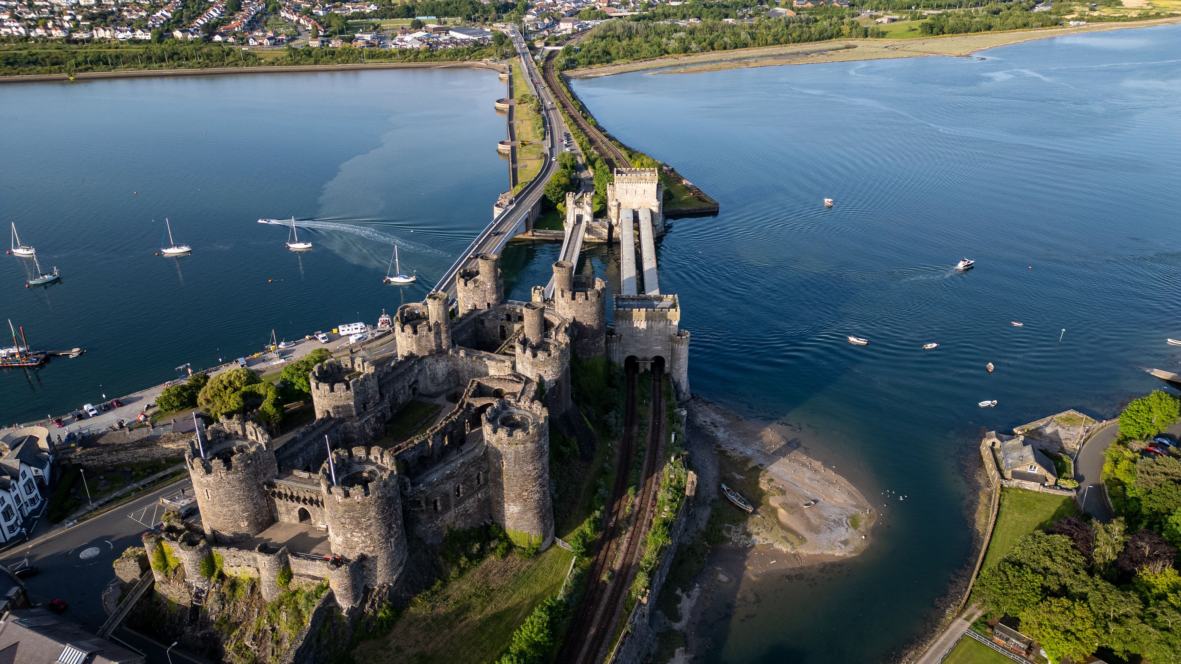 A castle by a river with boats and a bridge.