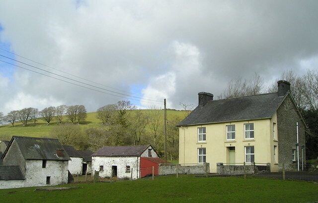 A rural landscape with a yellow house, a red house, and a white house.