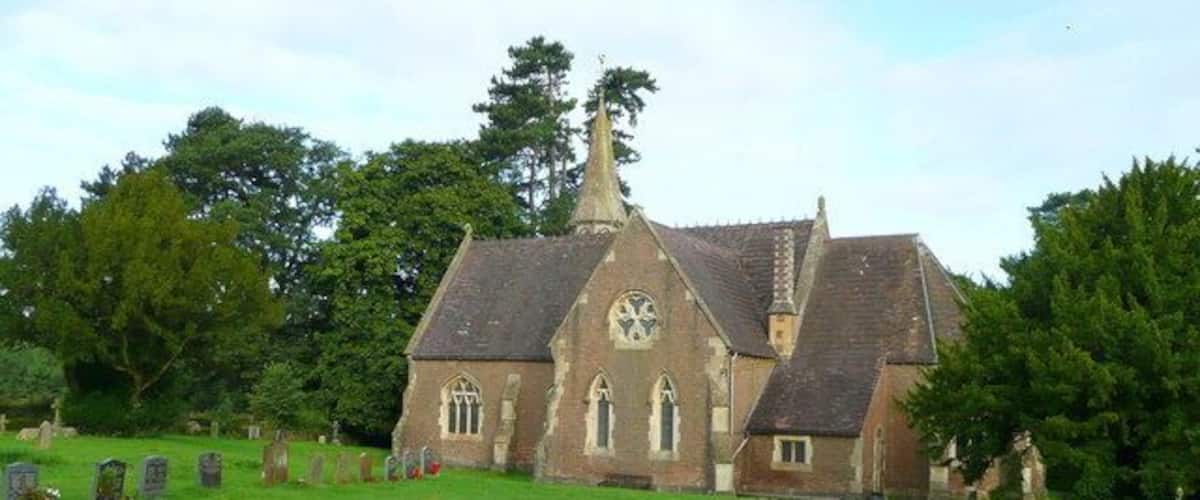 A church with a steeple, surrounded by a cemetery with headstones.